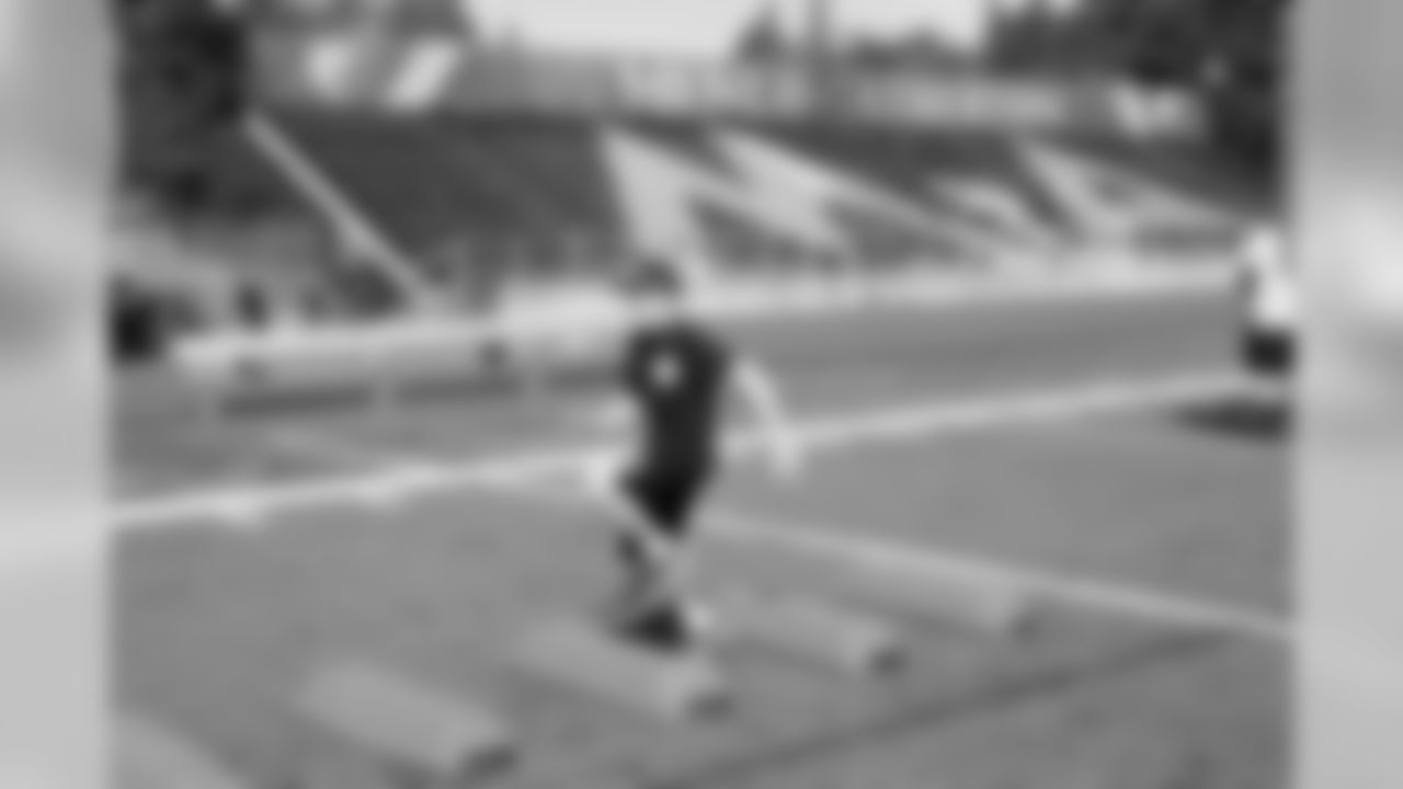 A Raiders fan and Camp One participant runs through a football drill.