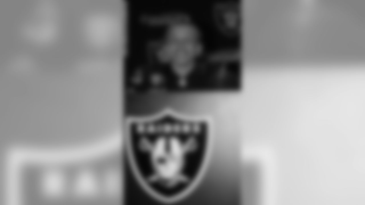 Frank poses for a photo at the podium in the Raiders auditorium.