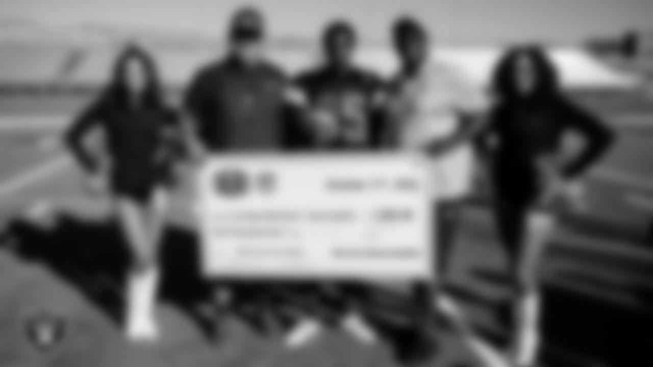 Raiderettes Kristian and Makenna P. and Las Vegas Raiders alumnus Reggie Kinlaw present Las Vegas High School coach, Erick Capetillo, the Tom Flores High School Coach of the Week award and Jahsire M. as the Most Outstanding Performer.