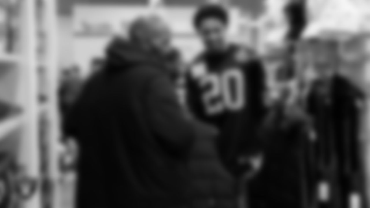 Las Vegas Raiders safety Isaiah Pola-Mao (20) goes around with a family as they pick out holiday food and gifts during Smith's Holiday Huddle.