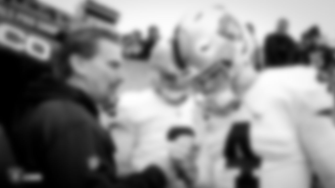 Oakland Raiders offensive coordinator Greg Olson, quarterback AJ McCarron (2), and quarterback Derek Carr (4) huddle up before their regular season game against the Cincinnati Bengals at Paul Brown Stadium, Sunday, December 16, 2018, in Cincinnati, Ohio. The Oakland Raiders lost 30-16.