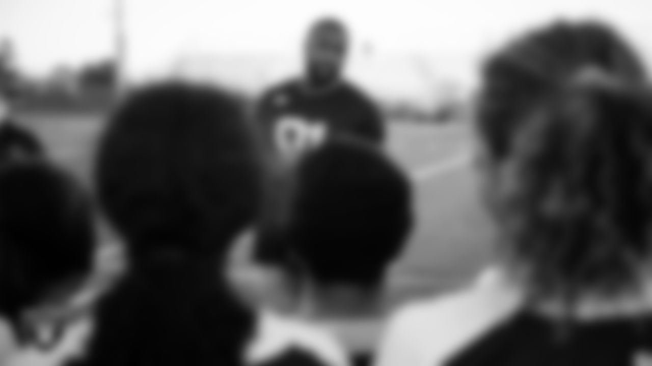 Las Vegas Raiders defensive end Yannick Ngakoue (91) speaks to the Del Sol Academy's girls flag football team before presenting their coach, Anne Schlosser, with the Tom Flores High School Coach of the Week award.