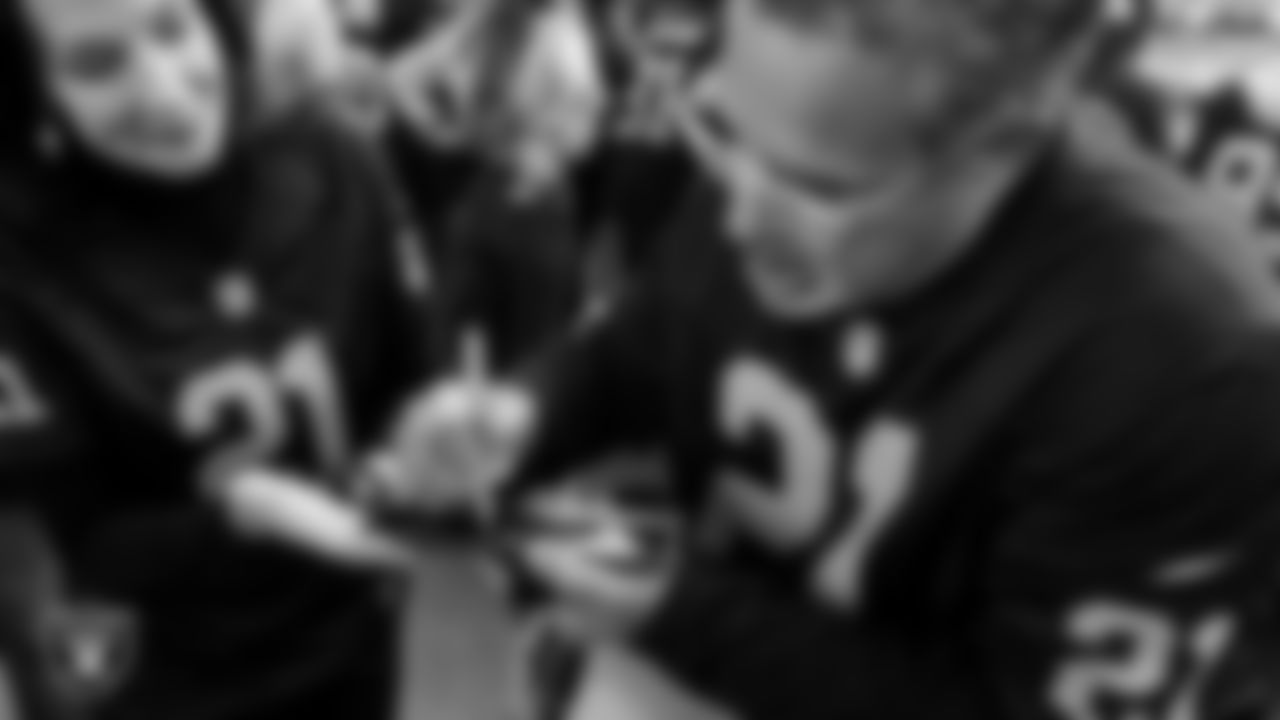 Member of the Las Vegas Chamber of Commerce Mary Beth Sewald and member of the Latin Chamber of Commerce Peter Guzman sign a plaque for the Al Davis Memorial torch before the Las Vegas Raiders' regular season home game against the Denver Broncos at Allegiant Stadium.