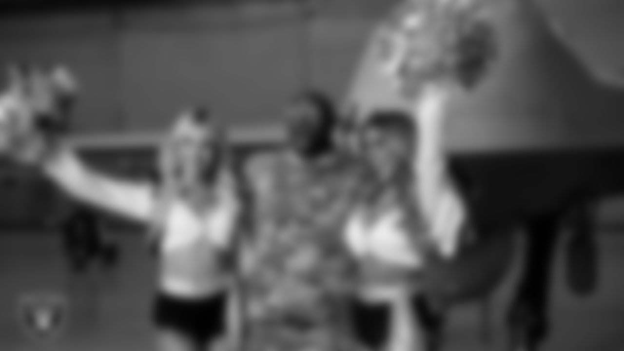 Raiderettes Madison and Bree pose for a photo with a service member at Creech Air Force Base during Operation Donut Drop.