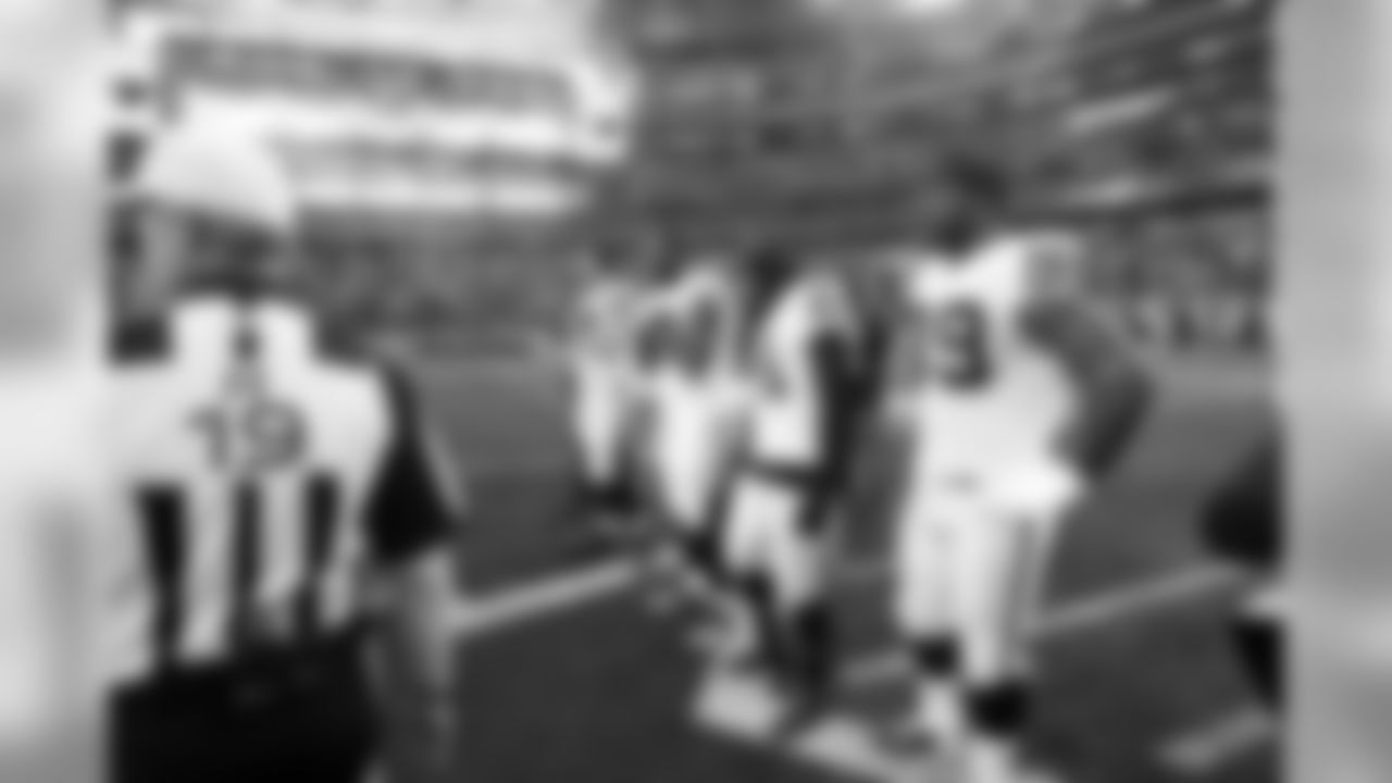 The captains wait for the coin toss at midfield.