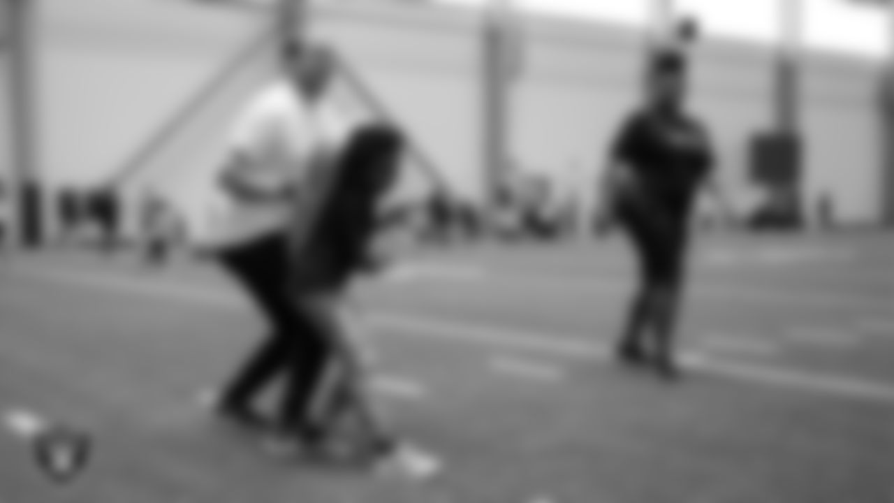 A Las Vegas Raiders volunteer works with a youth community member as they participate in a drill during Global Impact Day at Intermountain Health Performance Center.