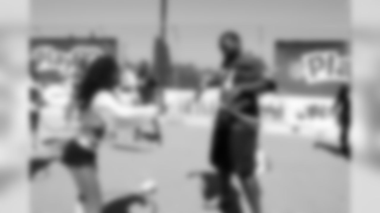 Raiderette Tori attempts to teach Ravens T Michael Oher how to hula hoop.