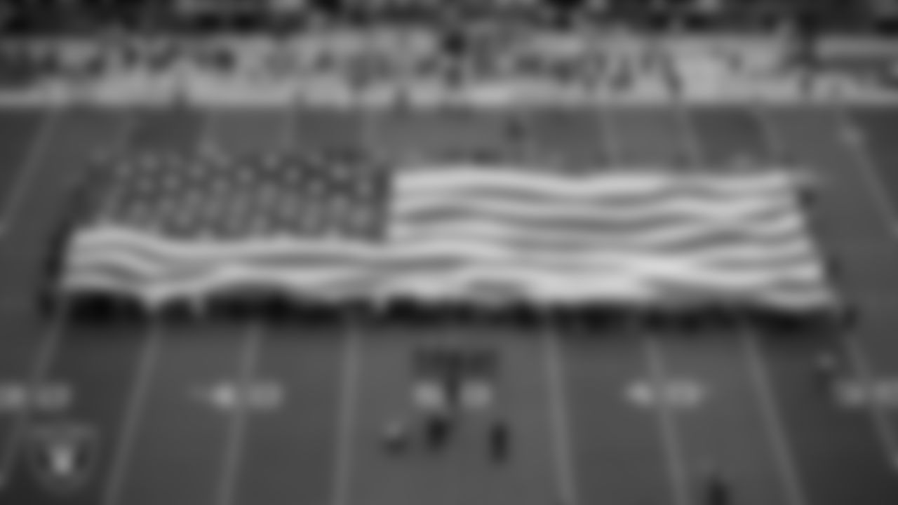 The American flag is displayed by Personal Seat License (PSL) holders on the field during the national anthem before the Las Vegas Raiders' regular season home game against the Denver Broncos at Allegiant Stadium.