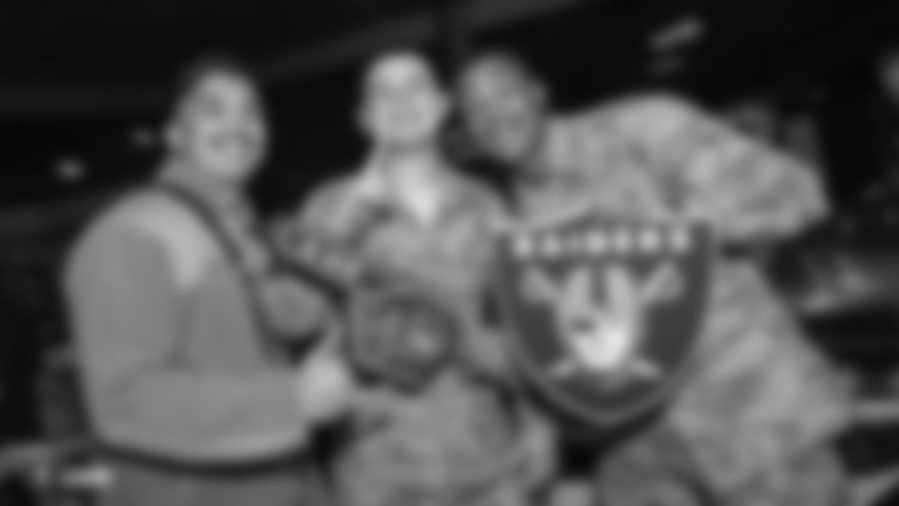 Troops pose for a photo with Raiders souvenirs at a Watch Party for members of the Las Vegas Raiders Family Association, troops from Nellis Air Force Base and their families during the Raiders regular season game against the New York Jets.