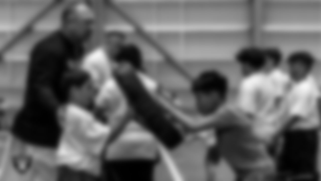 A coach works with athletes as they participate in drills during the ELITE Academy at the Las Vegas Raiders Headquarters.