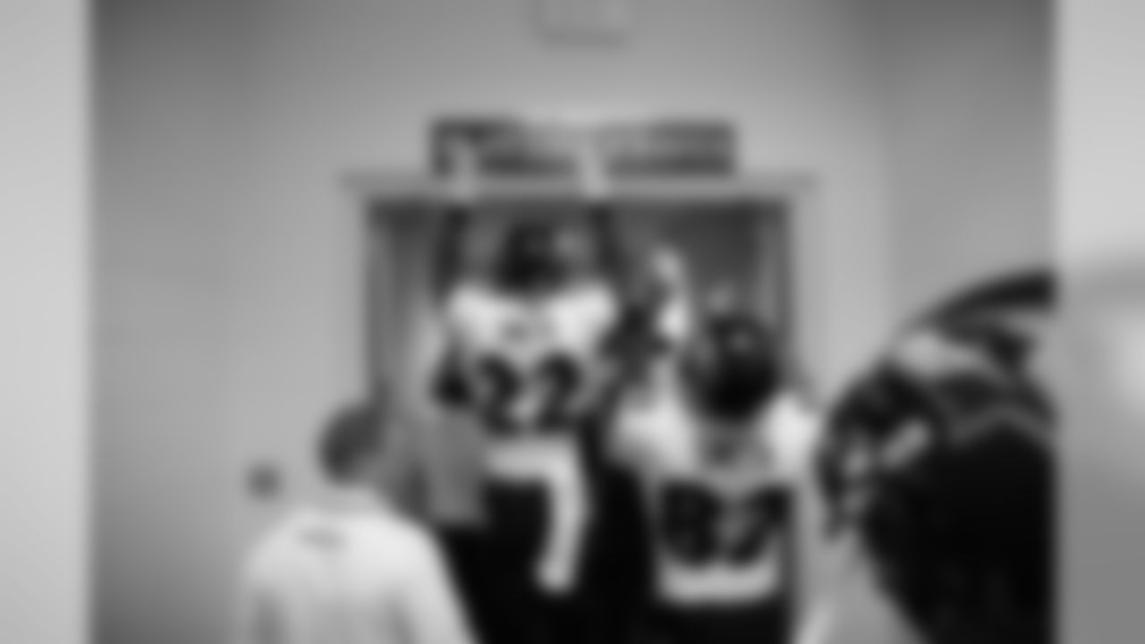 Ravens players slap their "Play Like A Raven" sign before exiting the locker room.