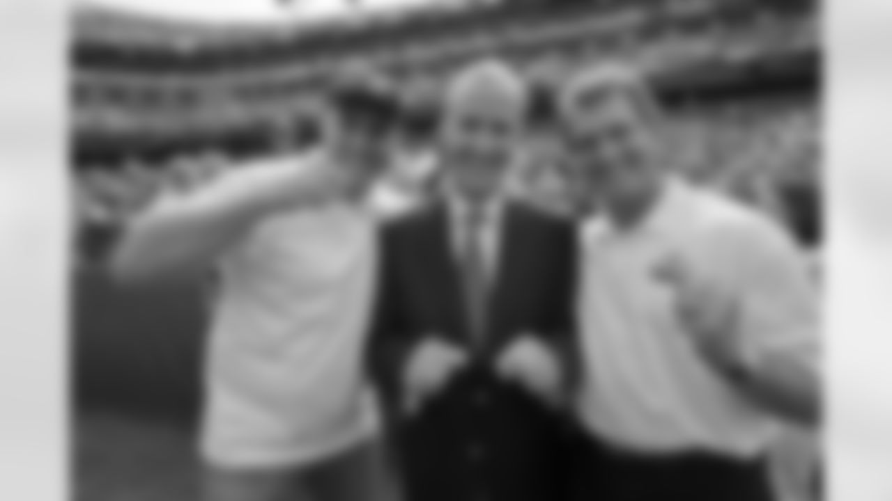 (left to right) Mark Rypien, NRG CEO David Crane, and Joe Theismann pose on the field before the Redskins-Cardinls game on Sunday.