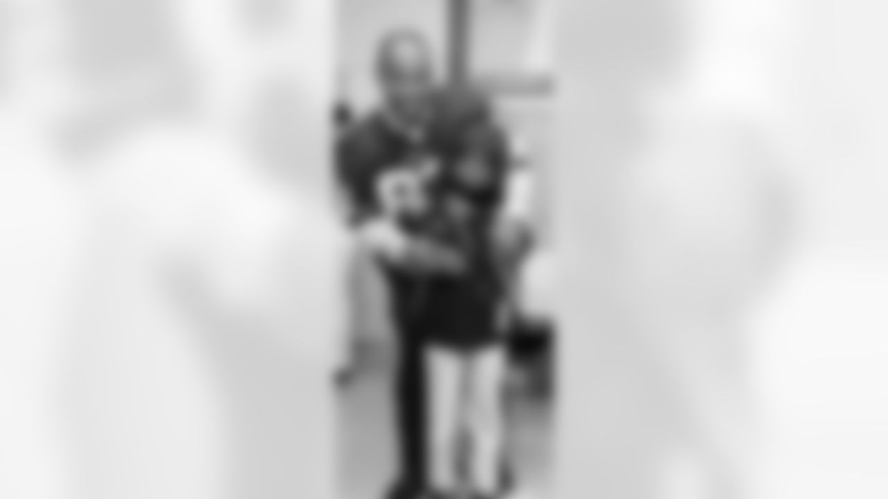 Antwaan Randle El fits a young boy with a coat.