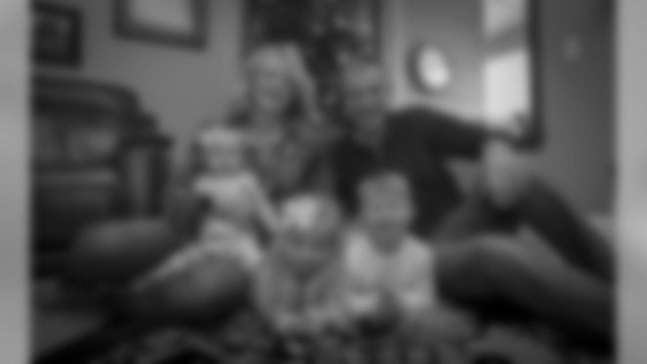 Doug and Natalie Hill pose in front of their Christmas tree with their grandchildren