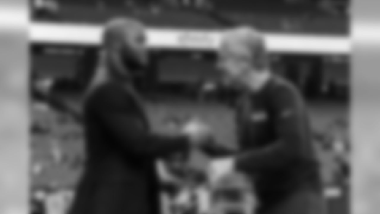 Seahawks head coach greets former player turned broadcaster Michael Robinson on the field before the game.