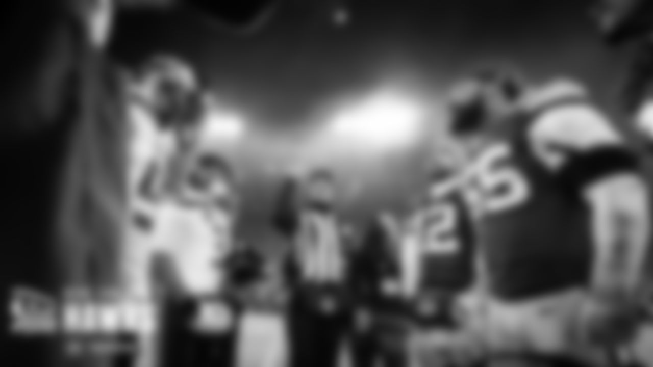 Head referee Clete Blakeman tosses the coin as team captains look on.