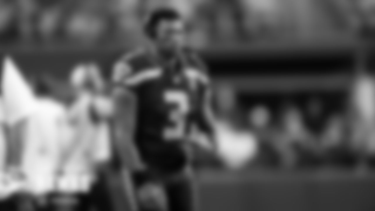 Quarterback Russell Wilson listens in via headset from the sidelines.