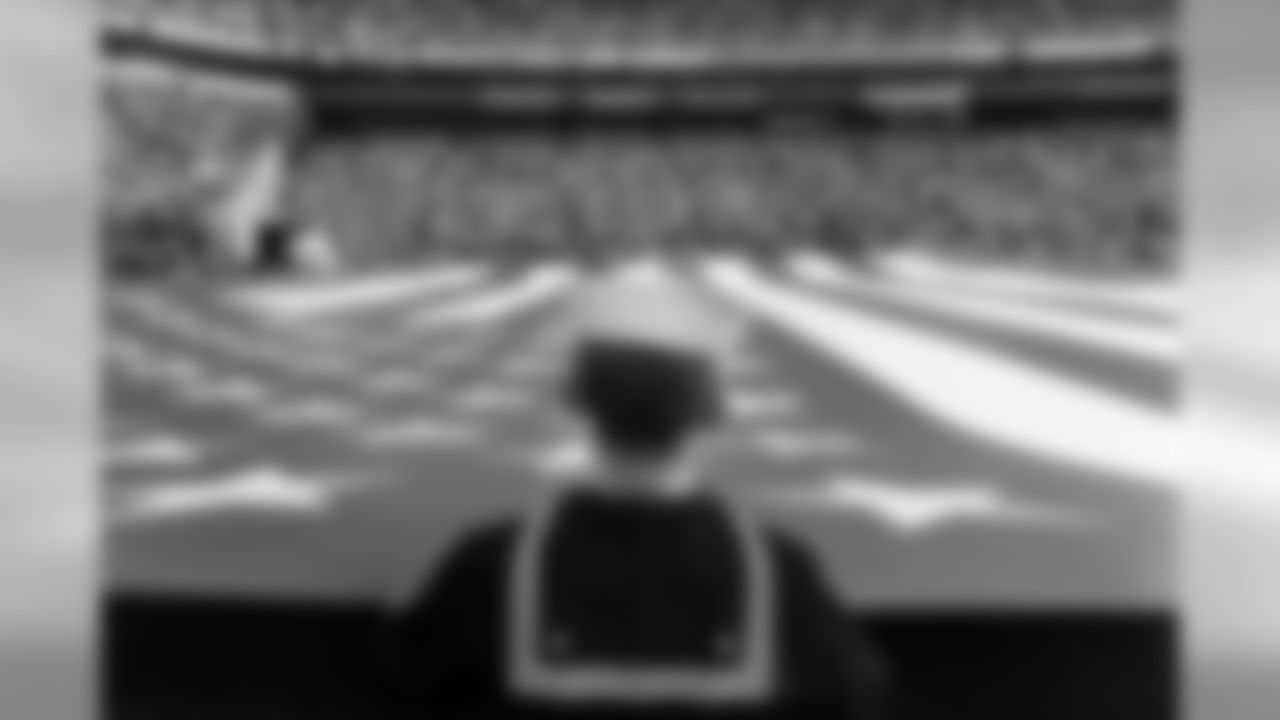 A member of the military helps hold the American flag aloft during the playing of the national anthem prior to kickoff.