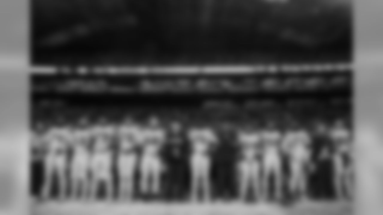The team stands arm-in-arm during their show of unity during the playing of the national anthem.