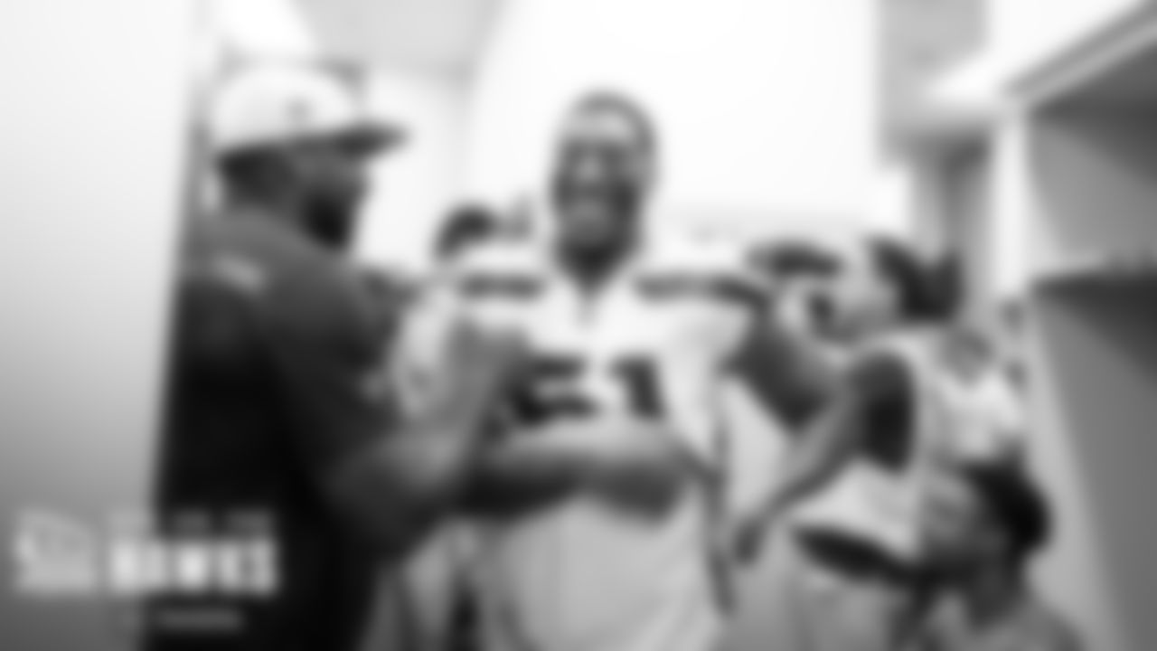 In the locker room, Bruce Irvin is congratulated by assitant coach Aaron Curry.
