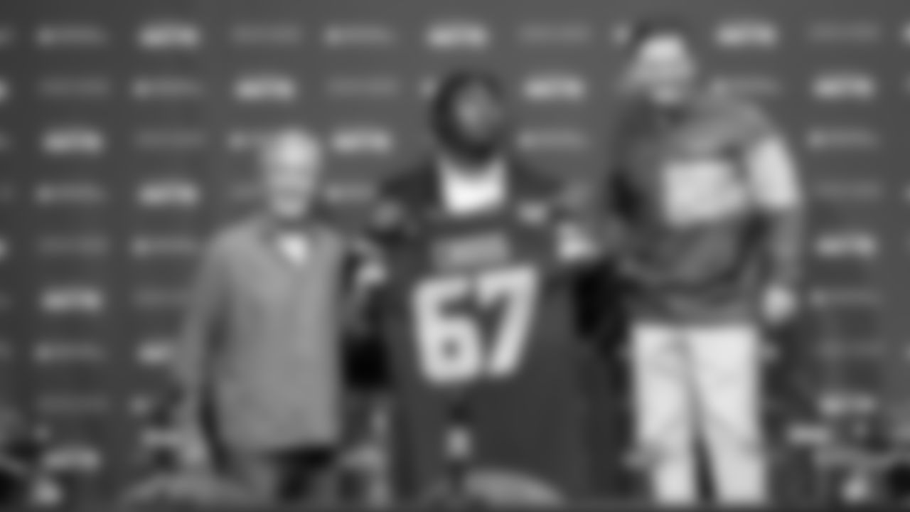 Seahawks first round draft pick Charles Cross looks up at general manager John Schneider, who jokingly stood on a chair to appear taller than the 6'5" Cross. At left is head coach Pete Carroll.