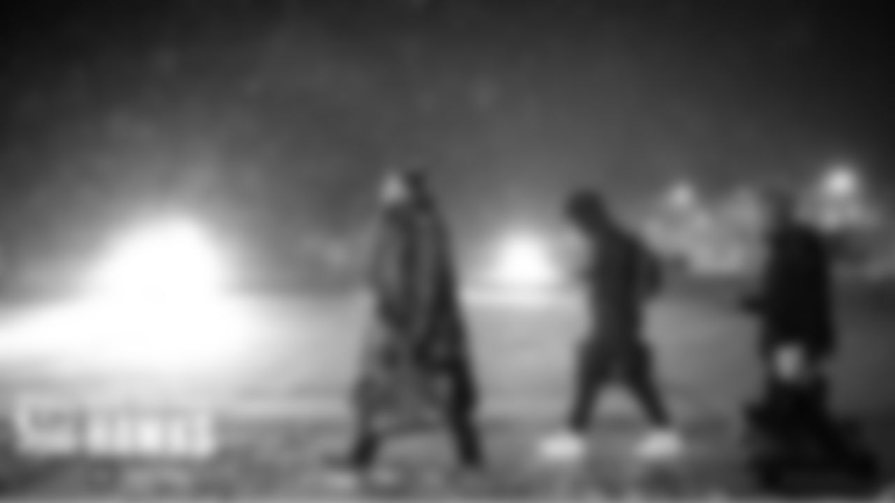 As snow fell late on Sunday evening, Seahawks offensive lineman Jordan Roos walks with teammates to their charter flight at the Green Bay airport for the return trip to Seattle.