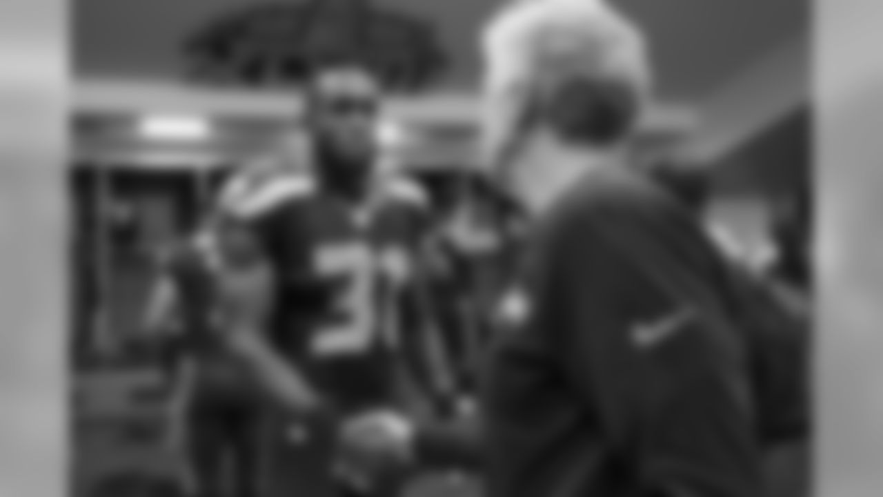 Strong safety Kam Chancellor accepts a congratulatory handshake from head coach Pete Carroll after the game in the locker room.