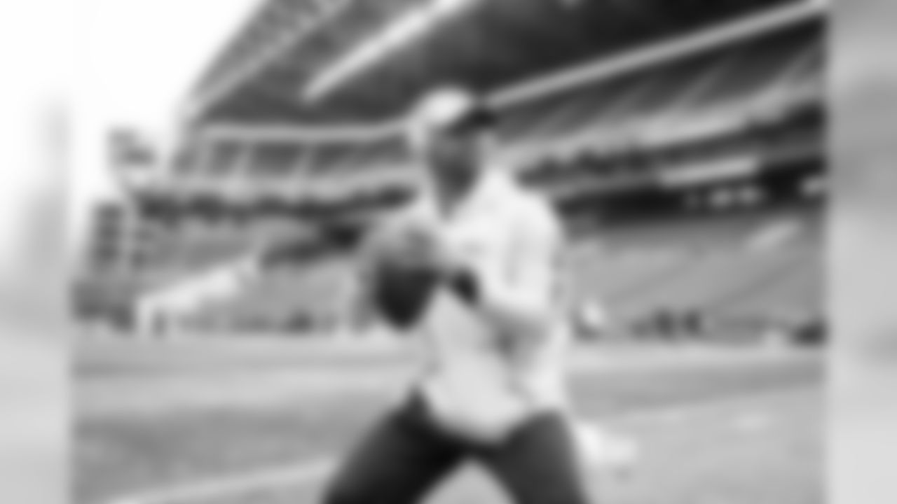 Quarterback Russell Wilson, wearing his Bose headphones, takes his early warmup throws in an empty stadium before fans arrive.