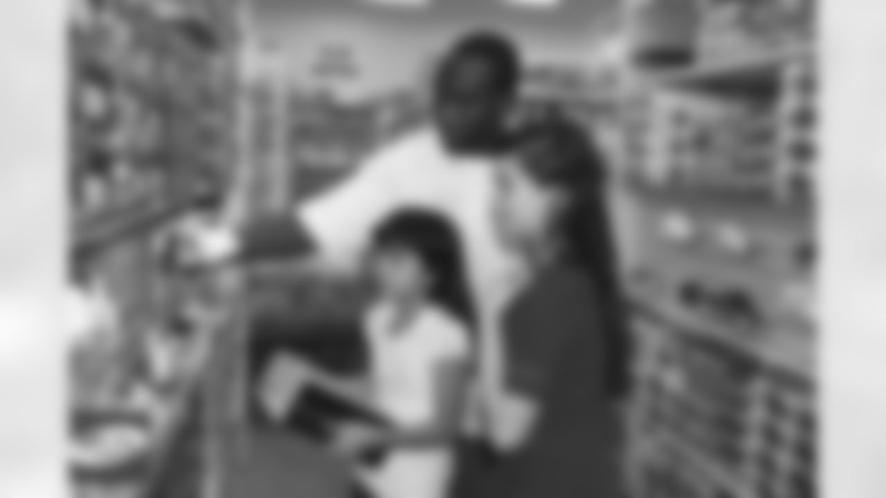 Rookie linebacker Xavier Adibi helps a child pick out a shoe.