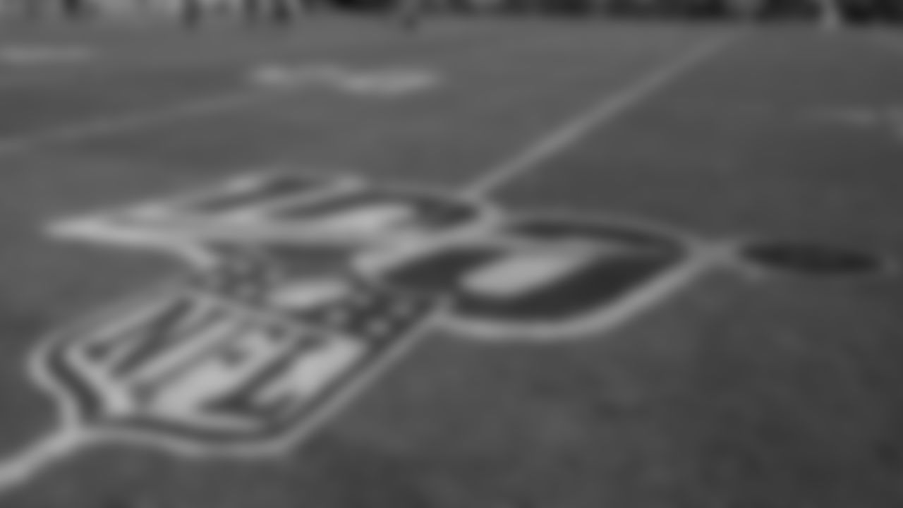 Players warm up behind a logo for the NFL's 100th anniversary before an NFL football game between the Tennessee Titans and the Indianapolis Colts Sunday, Sept. 15, 2019, in Nashville, Tenn. (AP Photo/James Kenney)