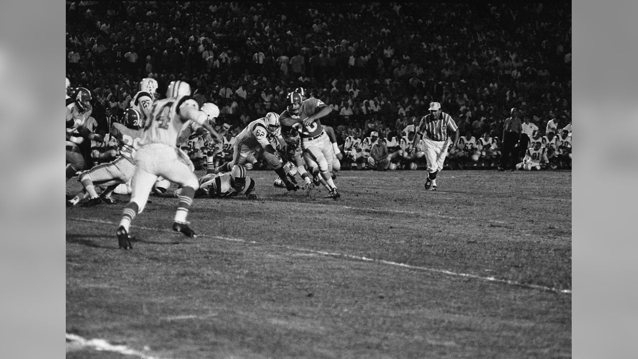 Billy Cannon (20), Houston Oilers halfback, jumps through a hole in the  line after taking a hand-off from quarterback George Blanda in first  quarter action against the Boston Patriots in the American