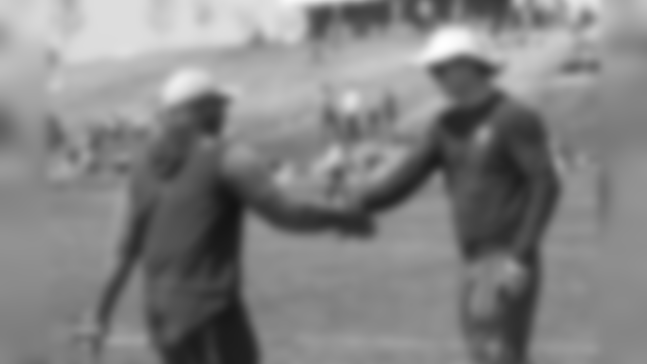 Head Coach Vance Joseph greets Peyton Manning with a handshake during a joint training camp practice with the Chicago Bears at UCHealth Training Center on August 16, 2018.