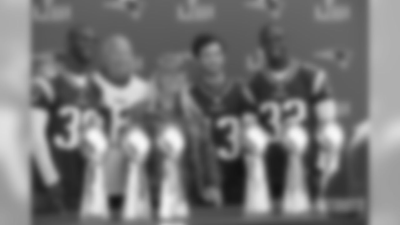 Participants pose with Devin and Jason McCourty for a photo in front of the Lombardi Trophies.