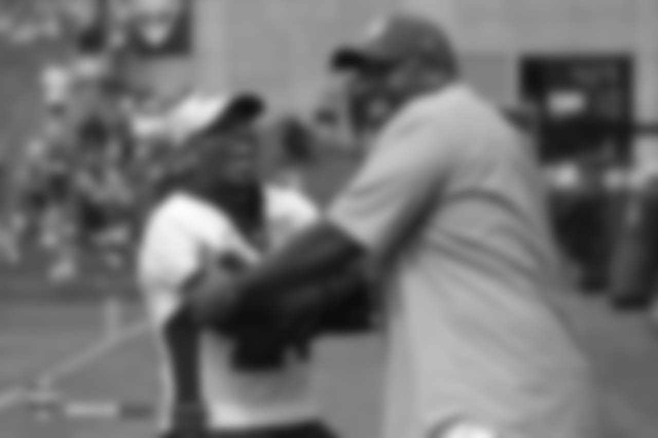 Cornerback Chris Harris Jr. (25) laughs as he talks with former Bronco Kevin Vickerson during the 10th day of training camp on August 8, 2018, at UCHealth Training Center.