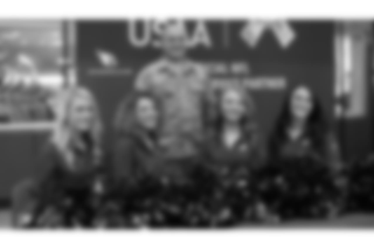 The Cardinals cheerleaders pose for a photo with a military member