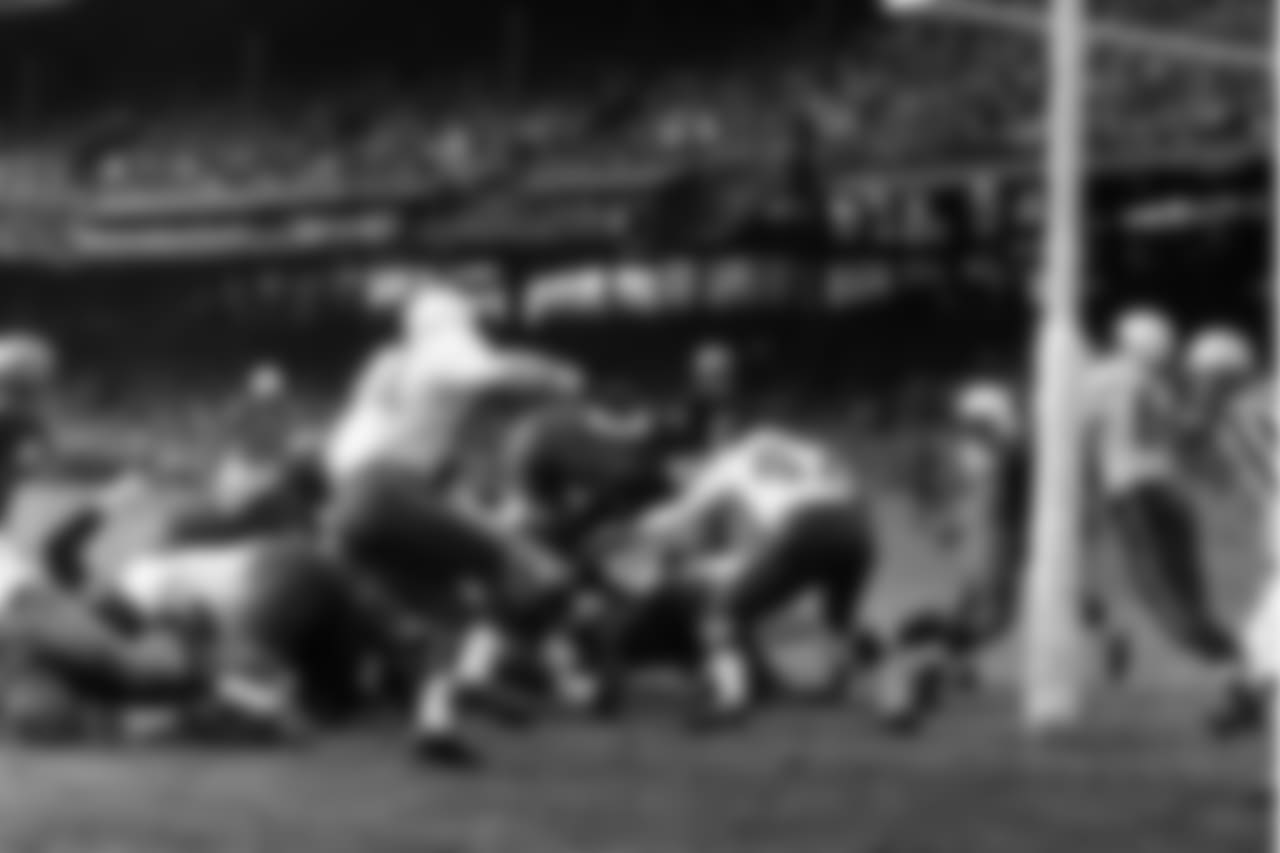Johnny Olszewski, Washington Redskins fullback, vaults across the line for a first-quarter touchdown against the Chicago Cardinals, Nov. 9, 1958, Washington, D.C. He is headed right for Bobby Gordon (47), Cardinal back. Dick Lane of the Cards is at left. Olszewski scored from one yard out.