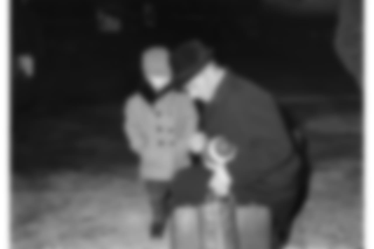 Laden down with luggage on arrival at Chicago's O'Hare Airport, New York Giants quarterback Y.A. Tittle stoops to autograph a football for three-year-old Joe Sambucci, Dec. 27, 1963. Giants play Chicago Bears Sunday in Wrigley Field for National Football League title. (AP Photo/Larry Stoddard)