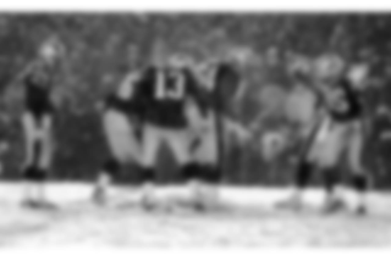 Patriots teammates clear the ground of snow with their feet, as they try to give Adam Vinatieri, far left, the best footing to kick the winning field goal in overtime. New England Patriots face the Oakland Raiders in an AFC playoff game at Foxboro Stadium in Foxborough, MA on Jan. 19, 2002.Â