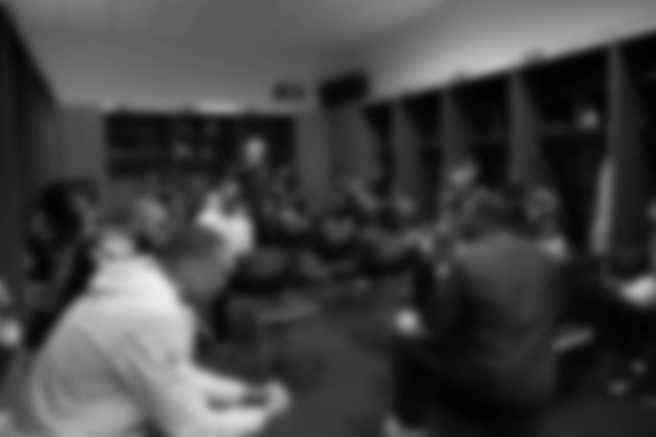 Head coach Pete Carroll stands near the back as the defense meets in the locker room at halftime.
