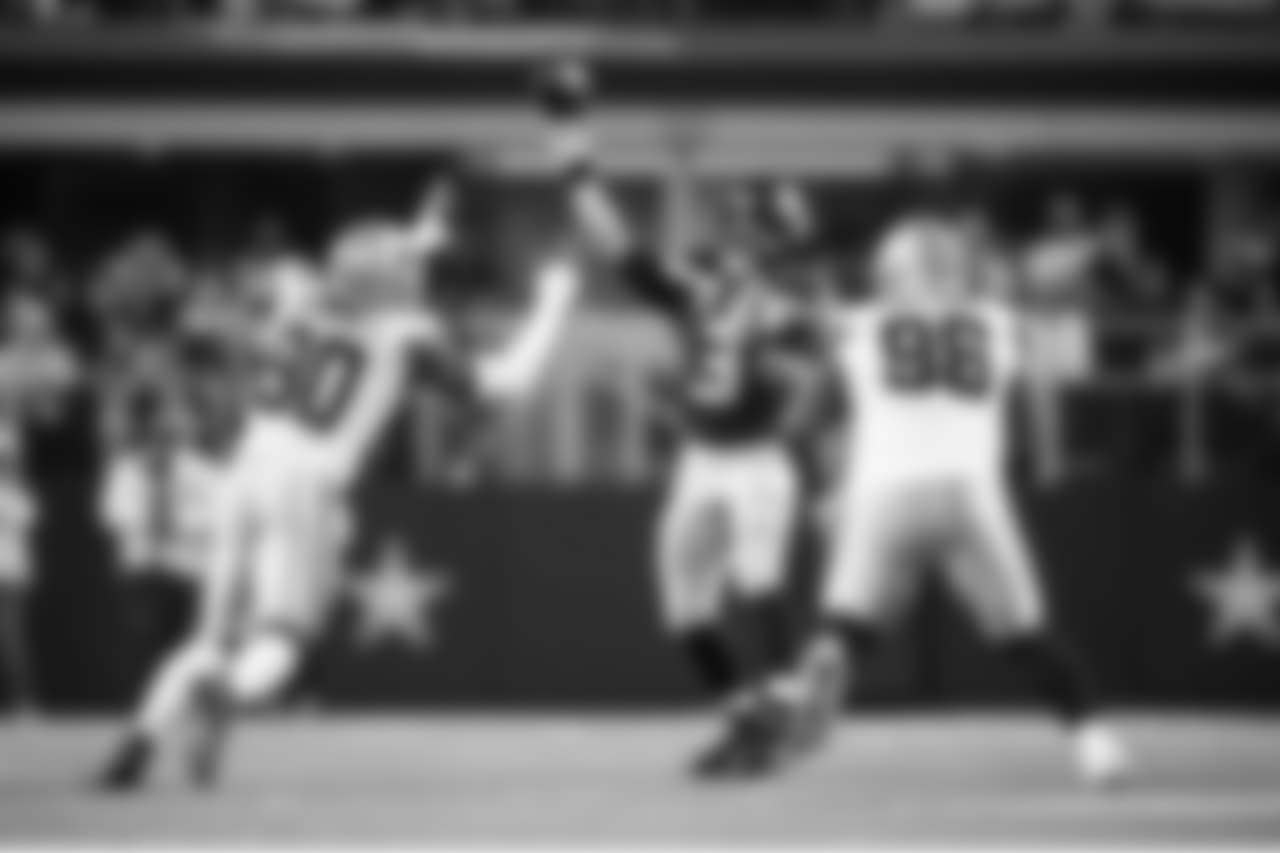 Seattle's Russell Wilson throws a pass as two Cowboys players close in.