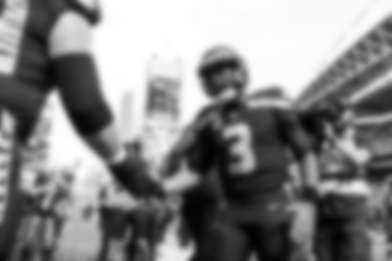 Quarterback Russell Wilson greets teammates as they take the field for pregame warmups prior to facing the visiting Dallas Cowboys.