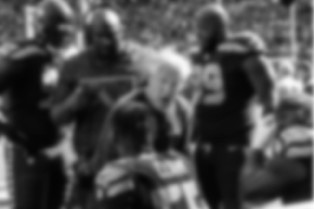 On the sidelines, head coach Pete Carroll talks to members of his defensive line.
