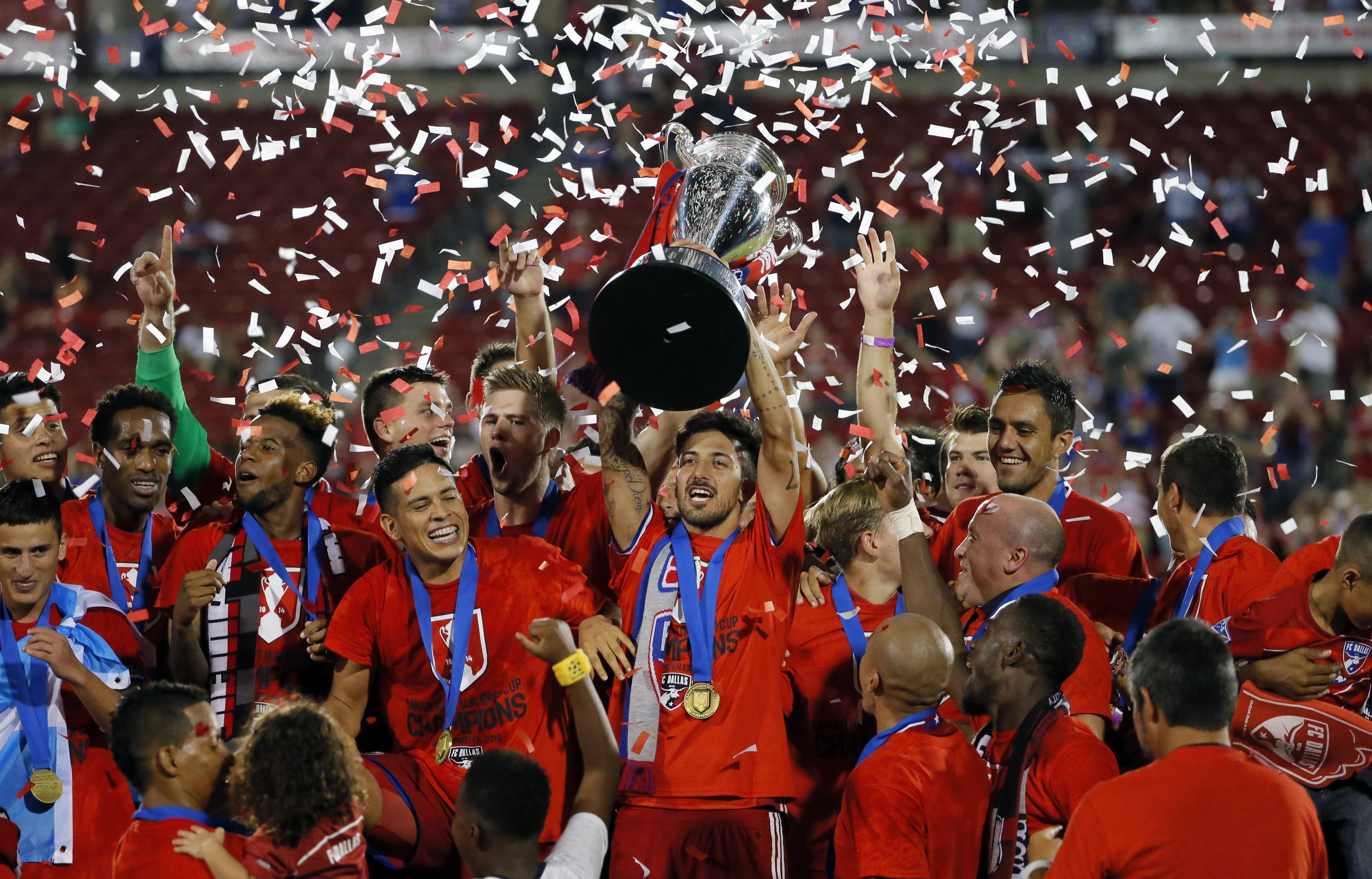 FC Dallas' Maximiliano Urruti holds the trophy as the team celebrates its 4-2 win over the New England Revolution in the U.S. Open Cup soccer final, Tuesday Sept. 13, 2016, in Frisco, Texas. (AP Photo/Tony Gutierrez)