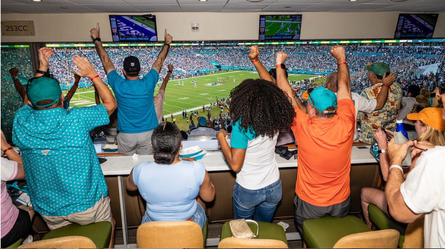 Photo of Dolphins fans cheering together in a suite