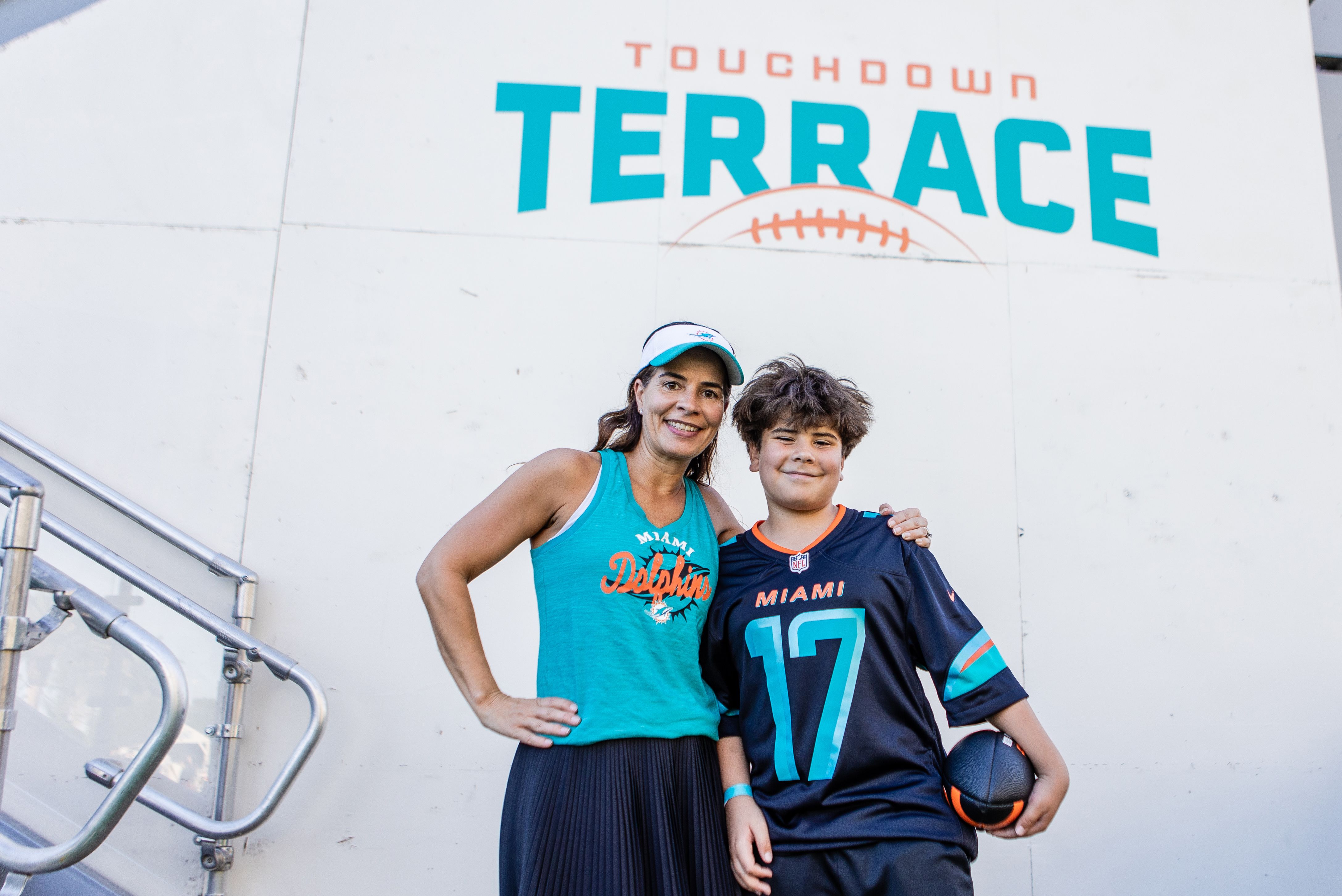 Little boy and mother posing in front of Touchdown terrace triangle sign during an NFL football game against the New York Jets on Sunday, March 30, 2025 in Miami Gardens, Fla. (Isabella Frias/Miami Dolphins via AP)