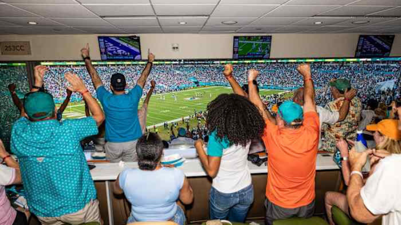 Photo of Dolphins fans cheering together in a suite