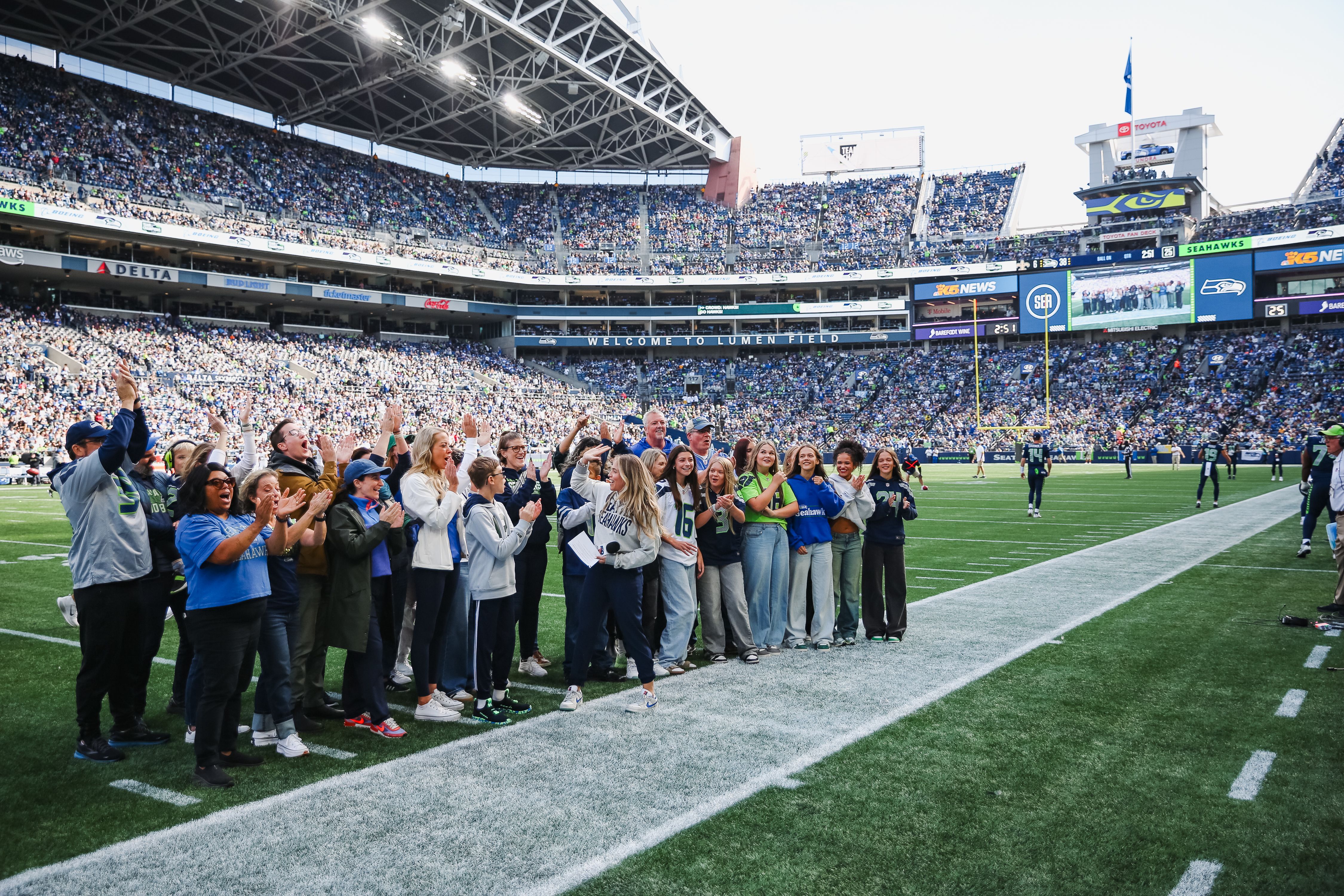 Group of people standing on the sideline of a Seahawks Game