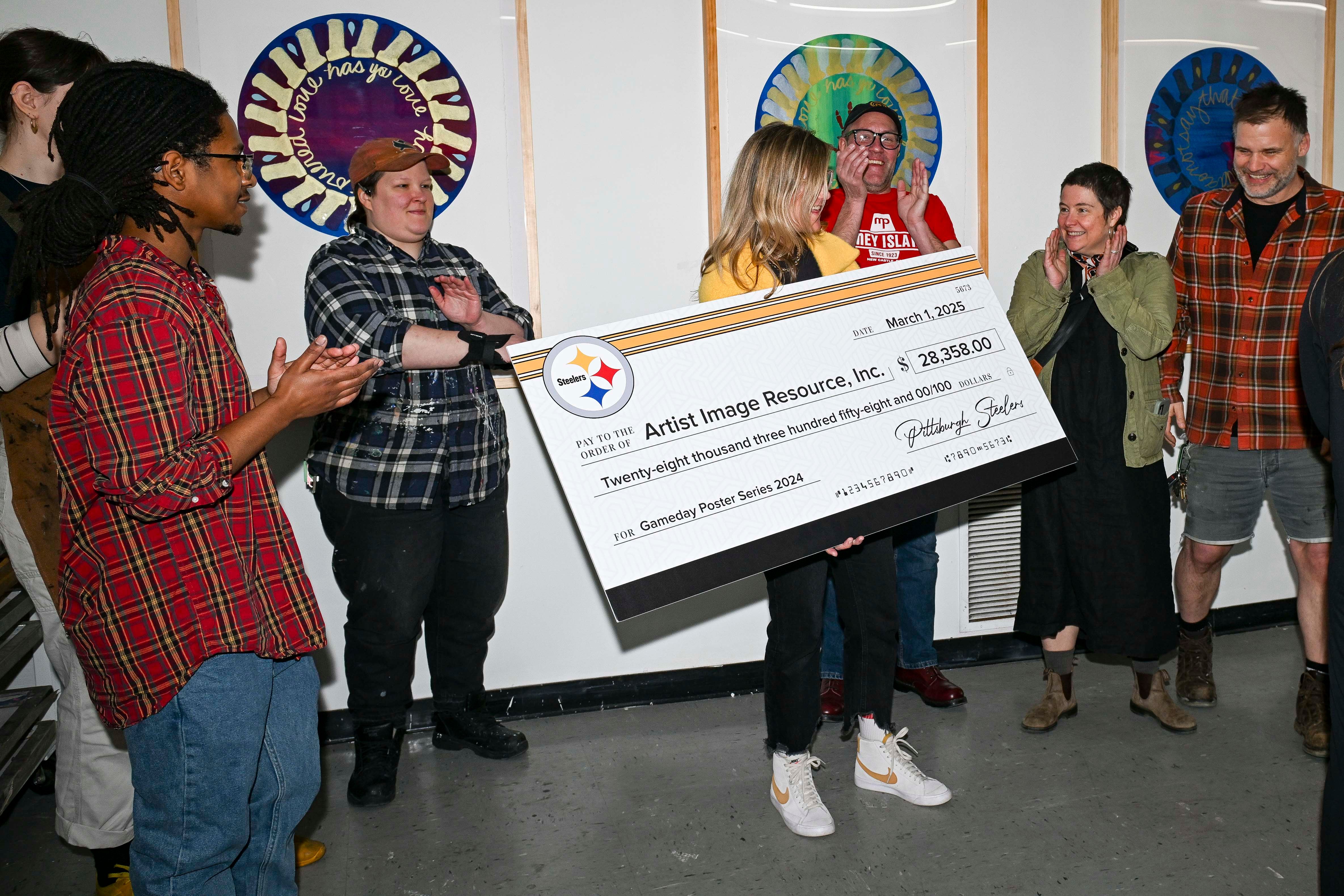 Artists Image Resource receives a check from the 2024 Gameday Poster Series, Wednesday, March 12, 2025 in Pittsburgh, PA. (Alysa Rubin / Pittsburgh Steelers)