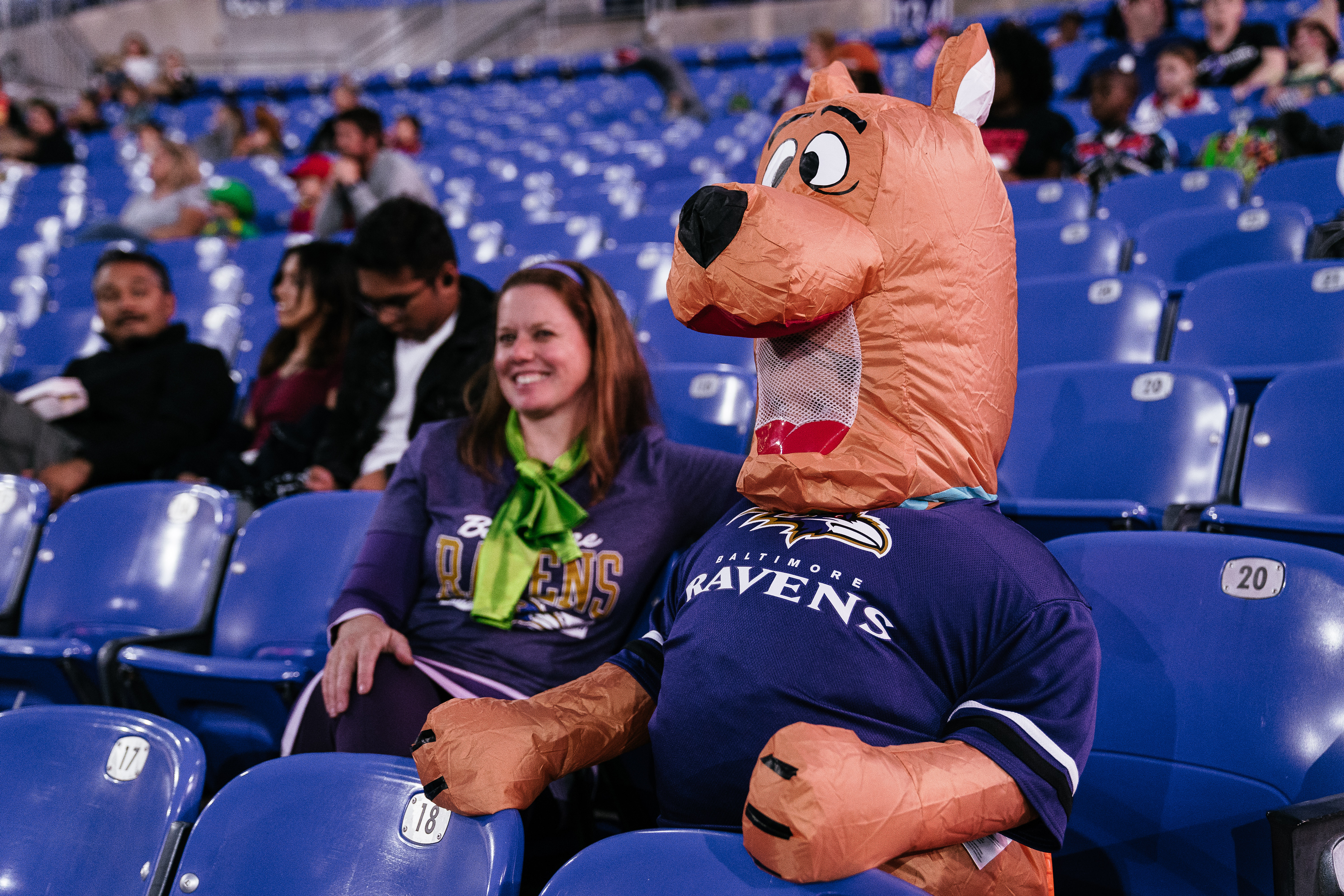 Fan in a Scooby-Doo costume sitting next to an inflatable Scooby-Doo wearing a Ravens jersey in the stadium seats