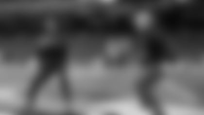 Quarterback Geno Smith drops back during early warmups as head coach Pete Carroll playfully "blitzes".